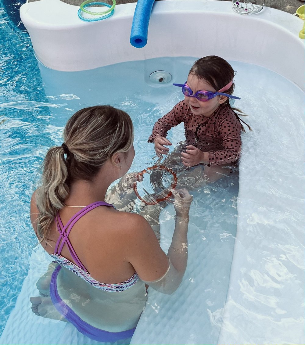 Une monitrice donne un cours de natation à une fillette dans une piscine creusée