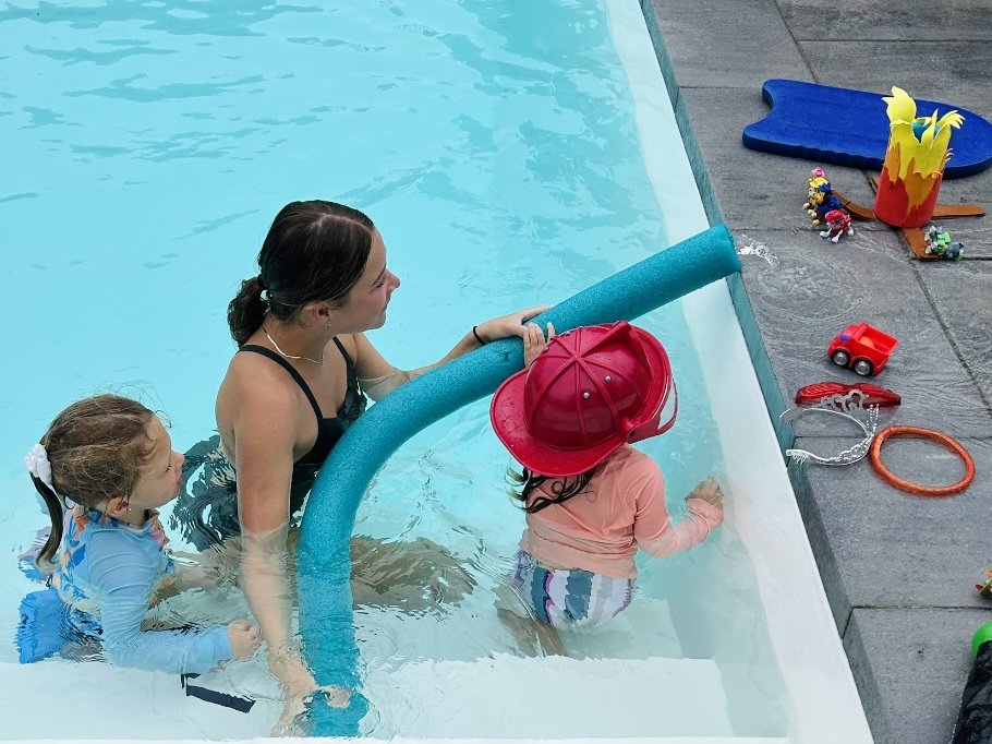 Une monitrice aquatique joue avec des enfants dans la piscine