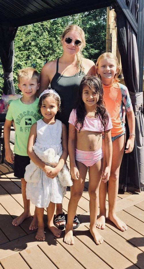 Une monitrice aquatique pose avec ses élèves lors d'un cours de natation à domicile pour enfants